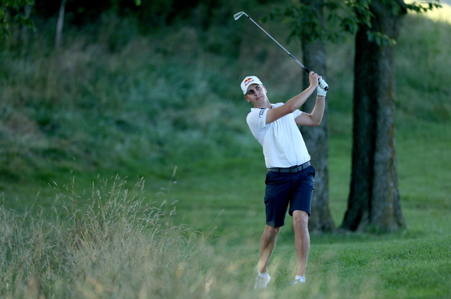 Ein Golfer schlägt nahe dem Rough mit dem Eisen