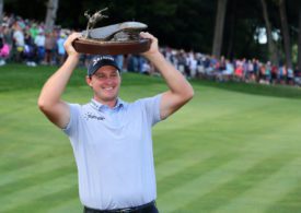 Ein Golfspieler stemmt eine Trophäe in die Luft