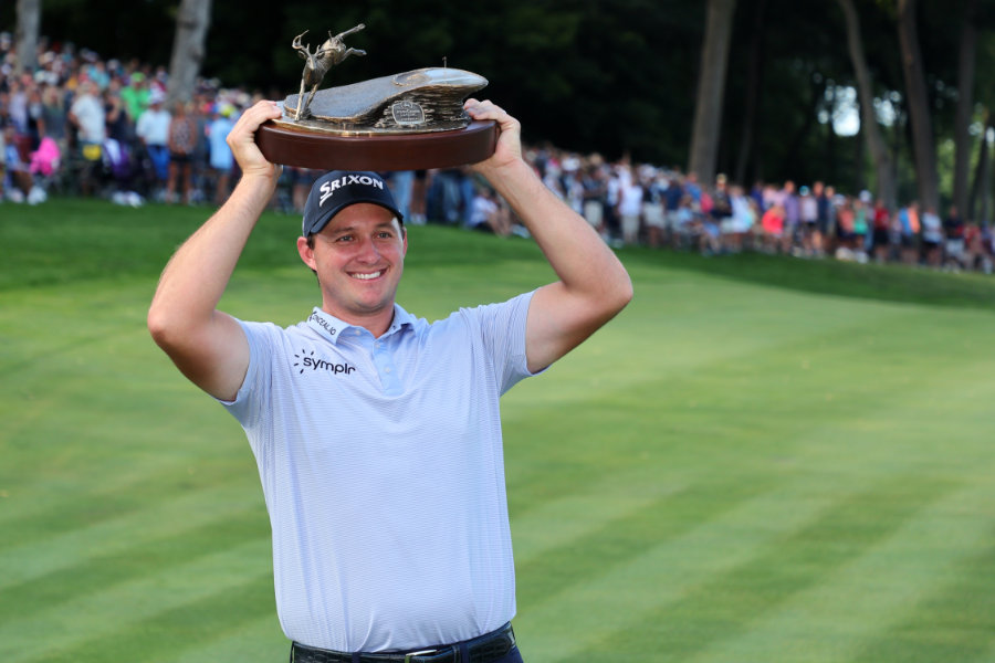 Ein Golfspieler stemmt eine Trophäe in die Luft