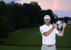 Lucas Glover mit der Trophäe der Wyndham Championship vor einem Regenbogen