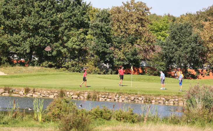 Golfer an einer Fahne vor einem Wasserhindernis