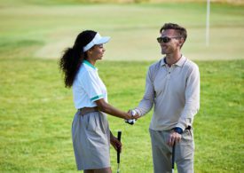 Eine Golferin und ein Golfer geben sich die Hand auf einem Golf Feld