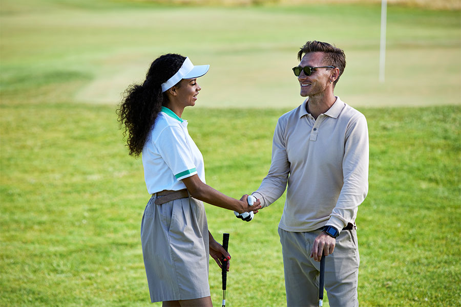 Eine Golferin und ein Golfer geben sich die Hand auf einem Golf Feld