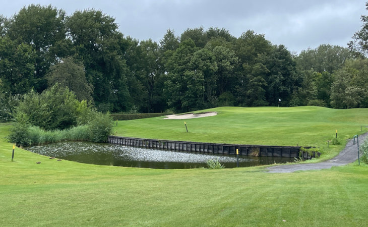 Ein Wasserhindernis vor einem Hügel auf einem Golfplatz