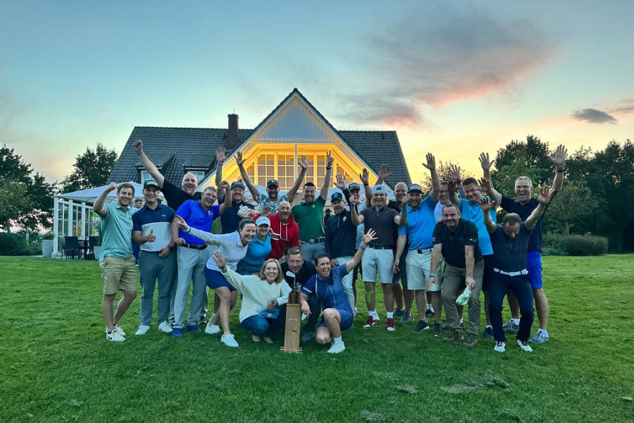 Viele Golfer bei einem gutgelaunten Gruppenfoto vor einem Clubhaus