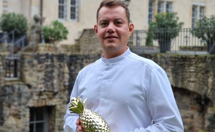Ein Koch posiert mit einer goldenen Ananas