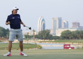 Ein Golfer jubelt, im Hintergrund sind Hochhäuser