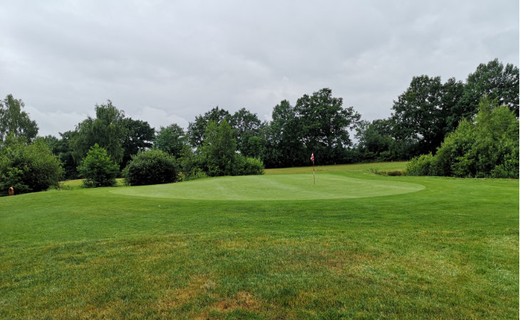 Ein Green mit Fahne auf einem Golfplatz