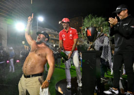 Ein Mann mit nacktem Oberkörper feiert vor einem Pokal