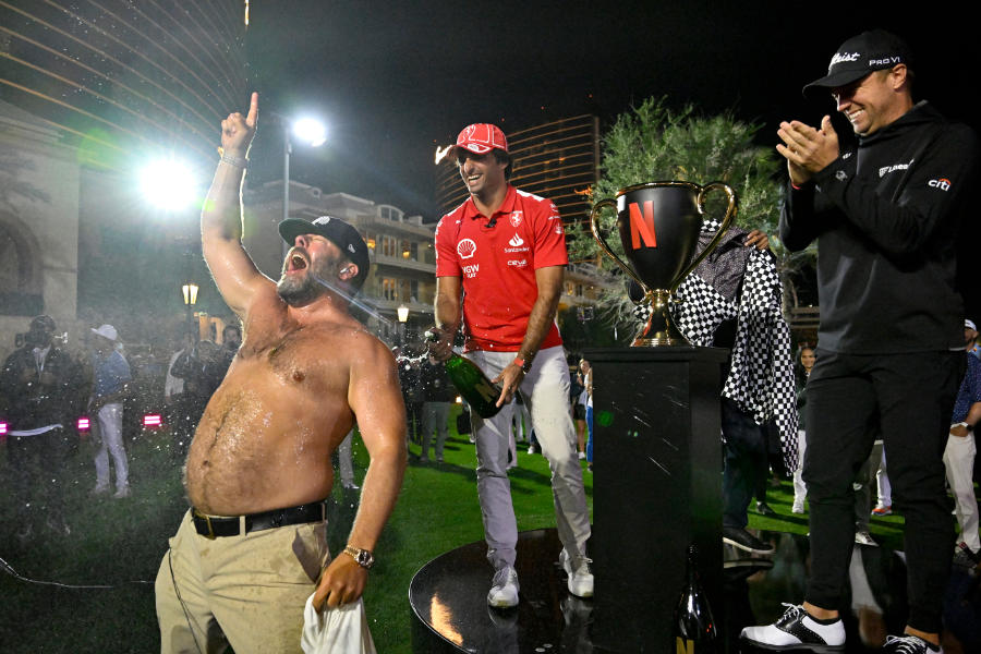 Ein Mann mit nacktem Oberkörper feiert vor einem Pokal