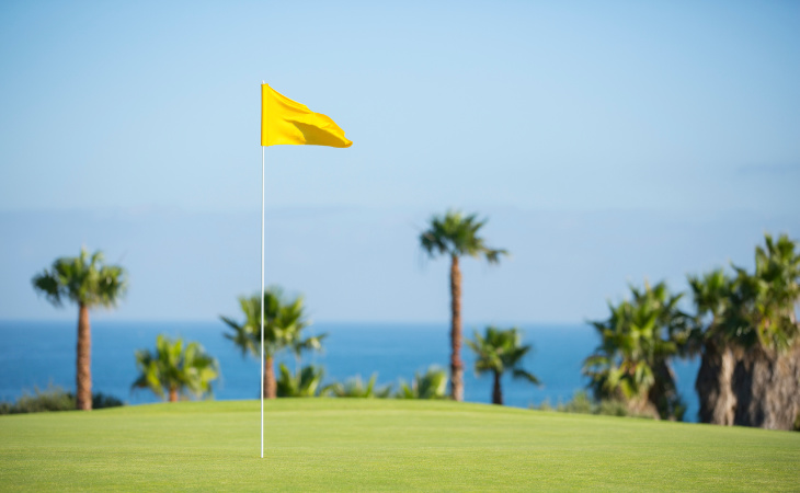 Eine gelbe Fahne auf einem Golfplatz weht im Wind