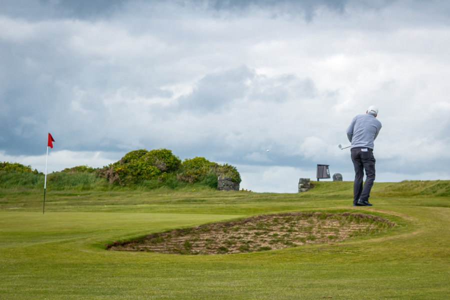 Ein Golfer auf dem Green bei bewölktem Himmel