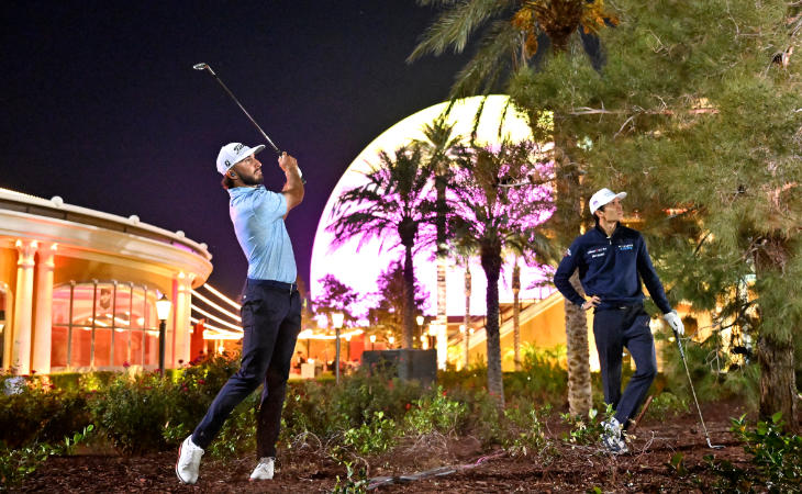 Zwei Golfer stehen im Rough mit buntem Hintergrund