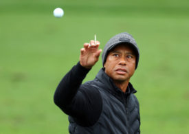Tiger Woods mit einem Tee in der Hand fängt einen Golfball auf