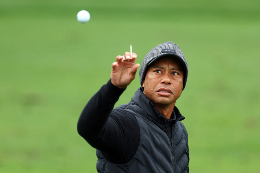 Tiger Woods mit einem Tee in der Hand fängt einen Golfball auf