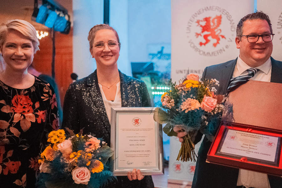 Ministerpräsidentin Manuela Schwesig sowie ein Mann und eine Frau mit Urkunden und Blumensträußen