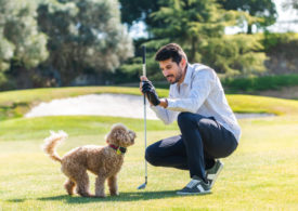 Ein Golfer mit einem kleinen Hund