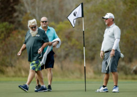 Drei Golfer auf dem Green mit schwarz-weißer Fahne