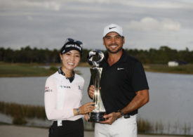 Ein Golfer und eine Golferin präsentieren gemeinsam eine Trophäe
