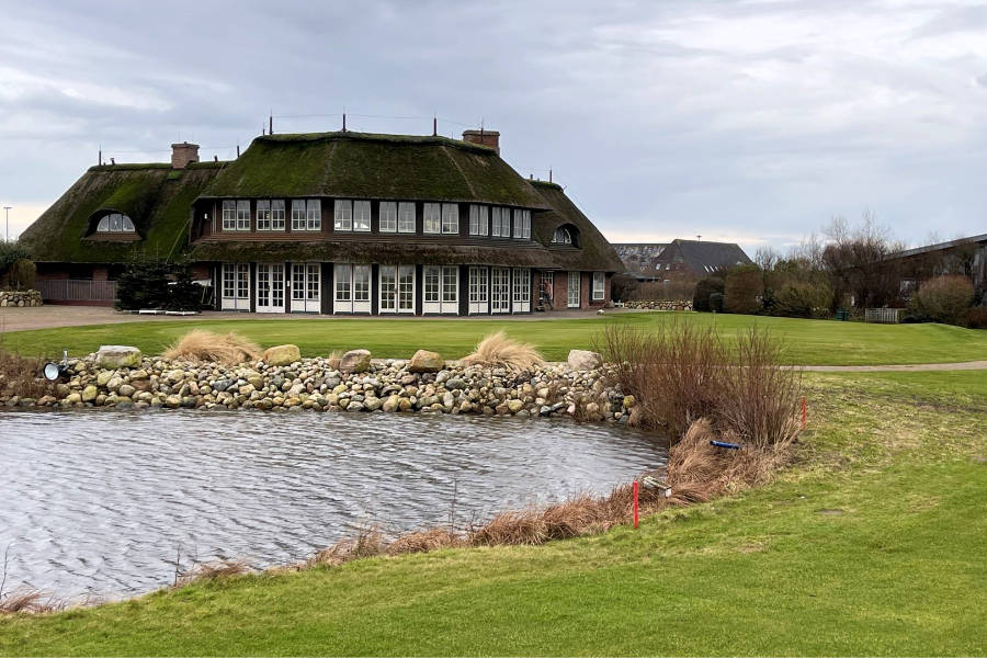 Das Clubhaus eines Golfclubs vor einem Teich