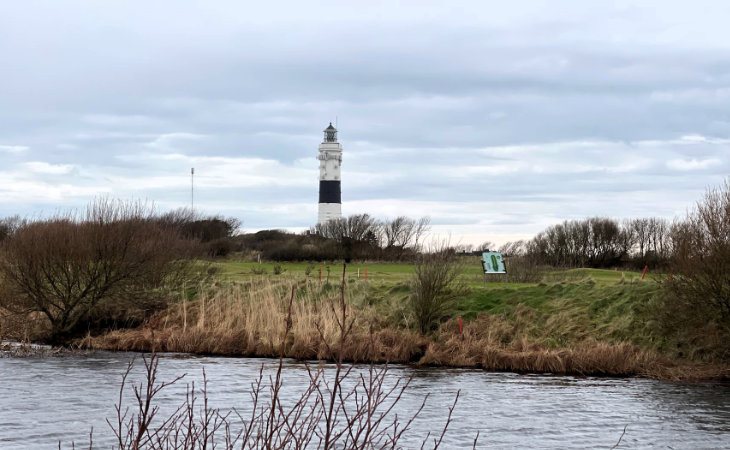 Blick von einem Golfplatz auf einen Leuchtturm