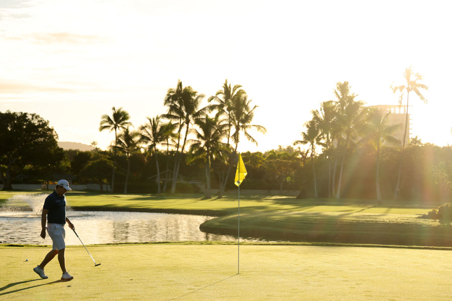 Ein Golfer auf einem Green vor Palmen und einem Sonnenuntergang