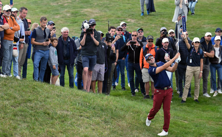 Ein Golfer schlägt vor Zuschauern auf einem Hügel ab