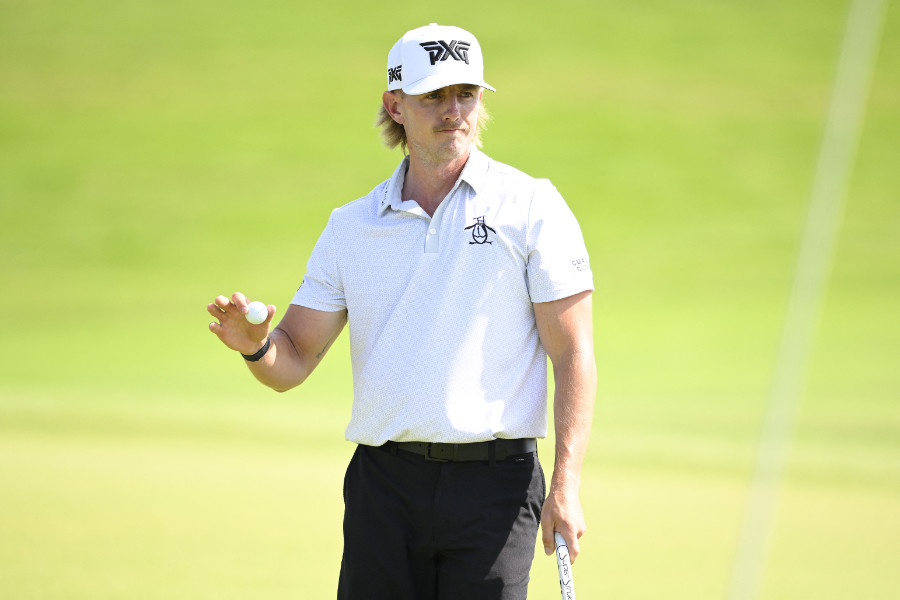 Golfer Jake Knapp hält einen Golfball in der einen Hand und einen Schläger in der anderen