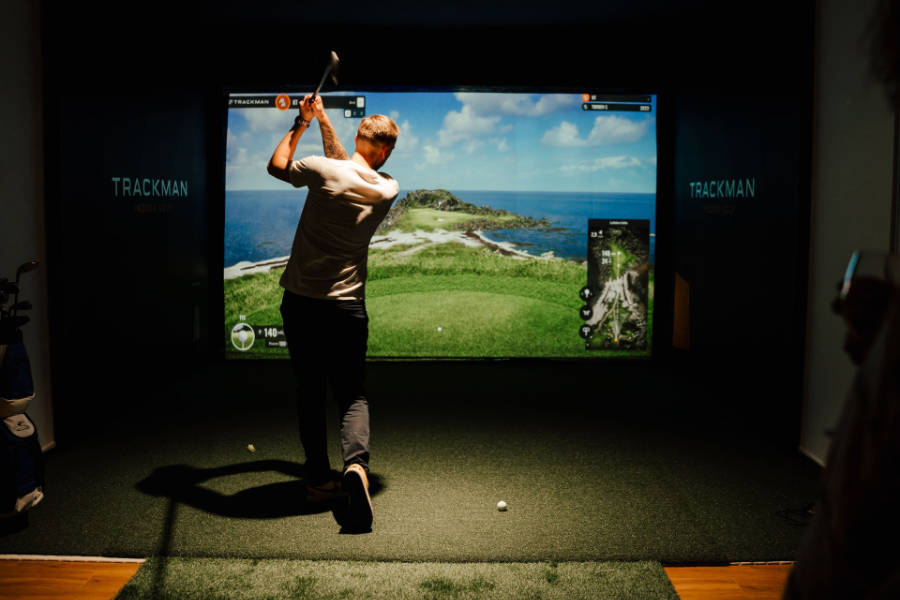 Ein Golfer schlägt auf einer Trackman Indoor Golfanlage ab