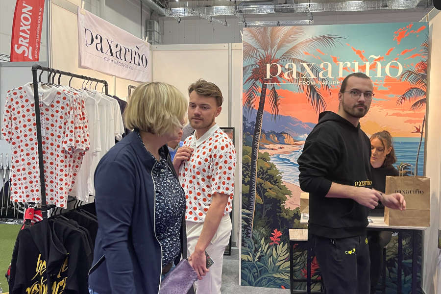 Menschen an einem Messestand mit bunten Golf-Shirts