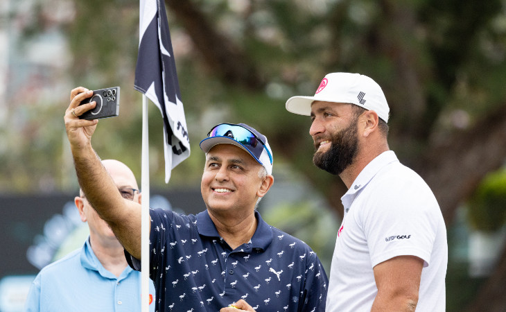Jon Rahm steht an einer Golf-Fahne und macht ein Selfie mit einem Zuschauer