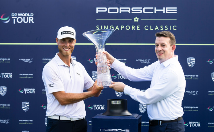 Ein Funktionär übergibt Jesper Svensson die Trophäe für den Sieg auf der Porsche Singapore Classic