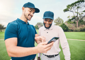 Zwei Golfer gucken auf ein Handy