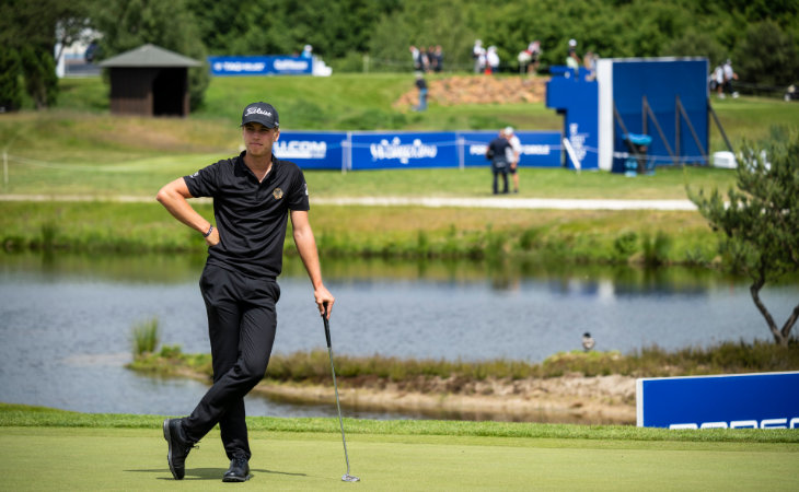 Tiger Christensen lehnt, auf einem Green stehend, auf seinem Putter