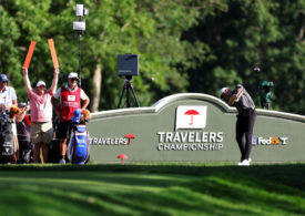 Keegan Bradley mit einem Abschlag vor einem Werbeschild der Travelers Championship