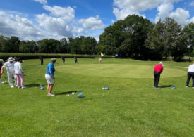 Mehrere Golfer bei einem Chipper Kurs rund um das Green