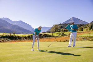 Ein Mann und eine Frau beim Golfen vor Bergpanorama